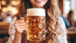 © Anoo - This beautiful young woman, clad in traditional Bavarian dress, joyfully raises a beer mug in celebration at Oktoberfest, embodying festive cheer and culture