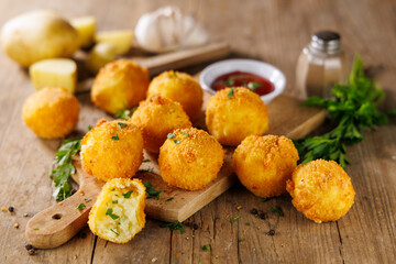 Poster - Deep Fried Potato Balls with Herbs and Ketchup – Tasty Snack on Wooden Background