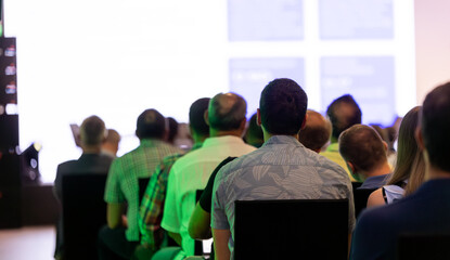 Wall Mural - rear view of the audience at a business conference meeting event listening to the speakers speech