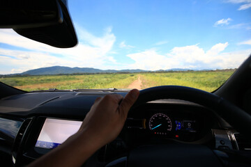 Wall Mural - A car driving through a scenic countryside road with mountains in the background and a clear blue sky