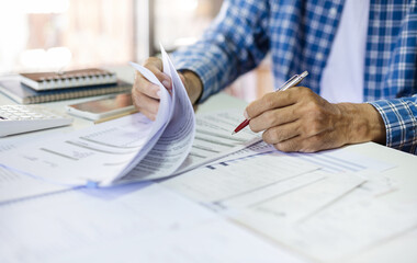 Asian man hands holding pen checking business document and various bills calculate income and expenses after start new business owner