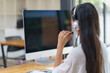 © Songsak C - Rear view of a female help desk operator. An office manager with a headset answers customer calls at the employee call center.