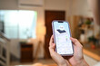 © Prathankarnpap - Woman holding a smartphone displaying a home energy monitoring app. Renewable energy concept