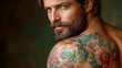 © imagineRbc - A man with a beard and tattoos on his arm. The tattoos are colorful and flowery. He is looking at the camera with a smile on his face