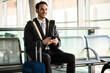 © Minerva Studio - Smiling businessman using smartphone at airport