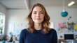 © JR-50 - A professional woman with wavy brown hair stands confidently in a bright office space, exuding a sense of determination and focus.