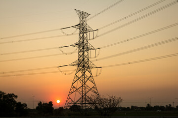 Hi-voltage electrical pole with sunset background.