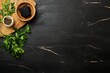 © Sanwa - A black marble countertop with a wooden cutting board, a small bowl of black peppercorns, a bowl of charcoal pieces and green parsley leaves.