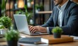 © Visual Sameer - Close up view of businessman typing on laptop while siting in meeting room with co worker and office supplies, Generative AI