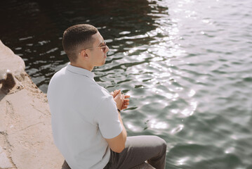 Portrait of a young arab male sitting on a pier near water edge. Generation Z Lebanese man