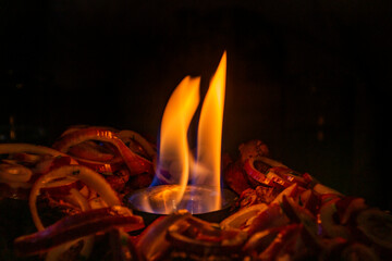 small Flame of fire among tasty onions in a dish in the dark close up