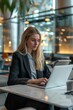 © Fotograf - Woman sitting at a table with a laptop, possibly working or browsing