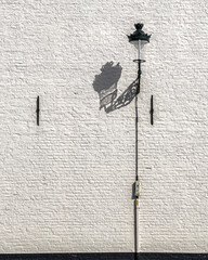 Architecture details of minimal white brick wall and the steel vintage street lamp with a beautiful shadow.