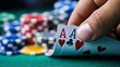 © ชลธิชา สว่างวงค์ - Close-up of a hand holding two aces in poker, with colorful chips scattered on a green felt table, capturing the thrill of gambling.