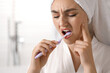© New Africa - Young woman suffering from toothache while brushing her teeth in bathroom