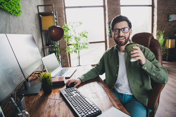 Poster - Photo of professional it specialist young man sit chair drink coffee computer desktop loft interior office indoors