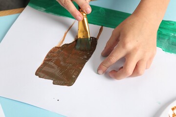 Canvas Print - Boy drawing picture with paint at light blue table, closeup