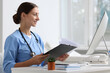 © New Africa - Nurse with clipboard at white table in clinic