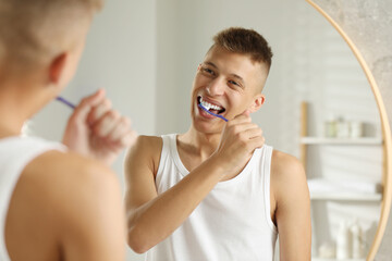 Canvas Print - Young man brushing his teeth in bathroom