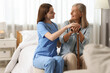 © New Africa - Smiling healthcare worker supporting senior patient on bed indoors