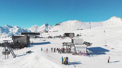 Wall Mural - Aerial overhead fly over groups of skiers on sunny day in Gudauri ski resort with mountains background in Georgia. Ski holidays in caucasus