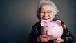 © Iona - An elderly woman joyfully holding a pink piggy bank, conveying happiness and financial security in her golden years.