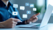 © P - A businessman using a laptop with social media icons floating above.  The image represents communication, technology, and digital marketing.