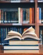 © SandraSevJarocka - Book in library with old open textbook, stack piles of literature text