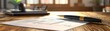 © K-Signature - Close-up of a pen and document on a wooden desk in a bright office setting, suggesting work, business, or study environment.