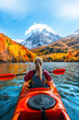 © Joyce - A person kayaking in water with colorful Autumn foliage woods