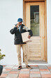 © peopleimages.com - Box, logistics and delivery man with phone call at front door for ecommerce, package and cargo tracking. Shipping, contact and communication with person and courier service at home for freight stock