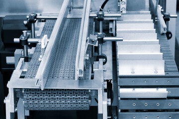 Poster - A conveyor belt with a white and silver color is moving. The conveyor belt is made of metal and has a silver color. It is moving at a steady pace and is transporting items from one place to another
