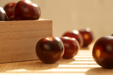 Cherry tomatoes of dark red color. Small tomatoes. Berries in a box. Fabric. Cooking at home. Harvest. Food. Wooden board.