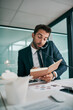 © SensSai/peopleimages.com - Business, man and phone call with diary in office for communication, connection and conversation. Male person, employee and telephonic meeting or multitasking for schedule, deadline and writing
