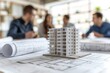 © Larisa - Miniature building model on blueprints with discussing people in
