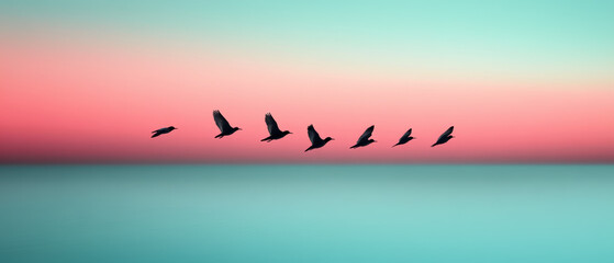 A group of birds flying in a row over a blue ocean