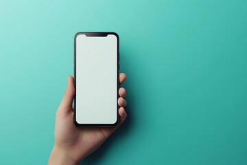 Hand holding a black smartphone with a blank white screen against a turquoise background.