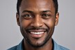 © ThomasLENNE - Full framed very close face portrait of a smiling 40s black man with gray eyes looking at the camera, studio shot,gray background.
