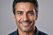 © ThomasLENNE - Full framed very close face portrait of a smiling 40s latin man with gray eyes looking at the camera, studio shot,gray background.