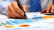 © Ndoomyim - Closeup Hand Analyzing Financial Data with Pen and Charts