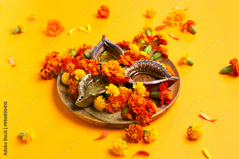 Diya lamp with marigold flowers on orange background. Divaly celebration