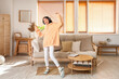 © Pixel-Shot - Young Asian woman in stylish hoodie with headphones dancing at home