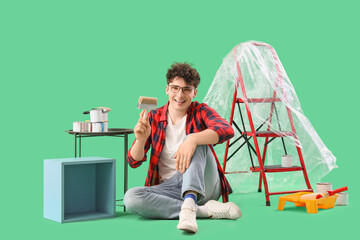 Poster - Young man with brush painting box on green background