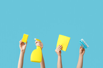 Wall Mural - Female hands holding sponge, rag, brush and bottle of detergent on blue background