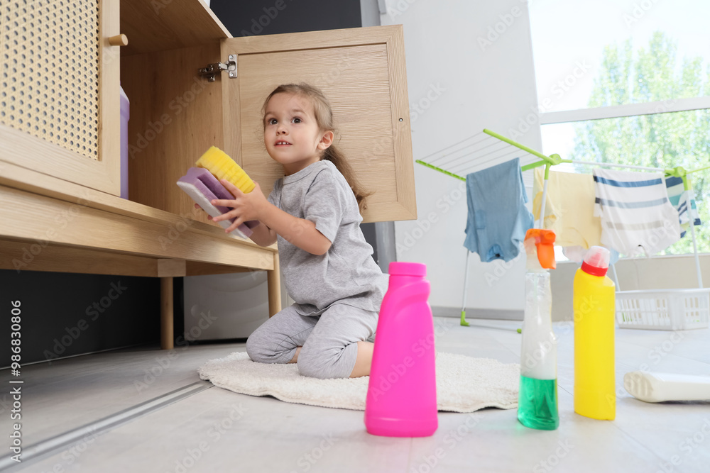 Cute little girl in laundry room. Child at risk