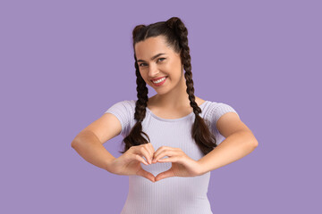 Poster - Beautiful young happy stylish woman with braids showing heart gesture on purple background