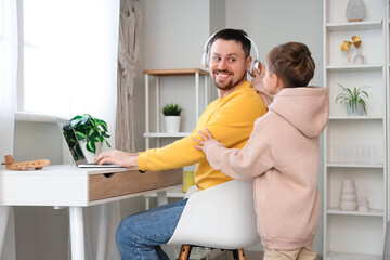 Sticker - Little son and his father in headphones working with laptop at home