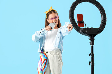 Sticker - Singing little girl with microphone recording video on blue background