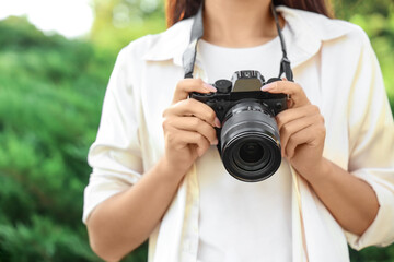 Wall Mural - Female photographer with camera in park, closeup