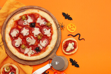 Canvas Print - Composition with tasty pizzas, cutter and decorations for Halloween on orange background